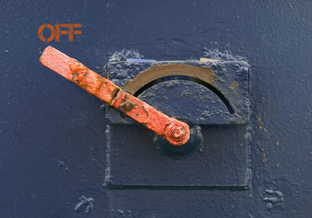 Turn off the camp machine. Image of metal lever painted orange turned to the left pointed to the word off, painted on blue wall.