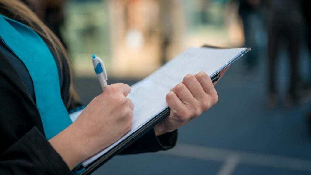 Image of person standing and writing on paper.