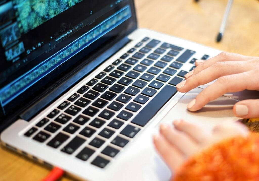 Hands of a person editing video on a laptop