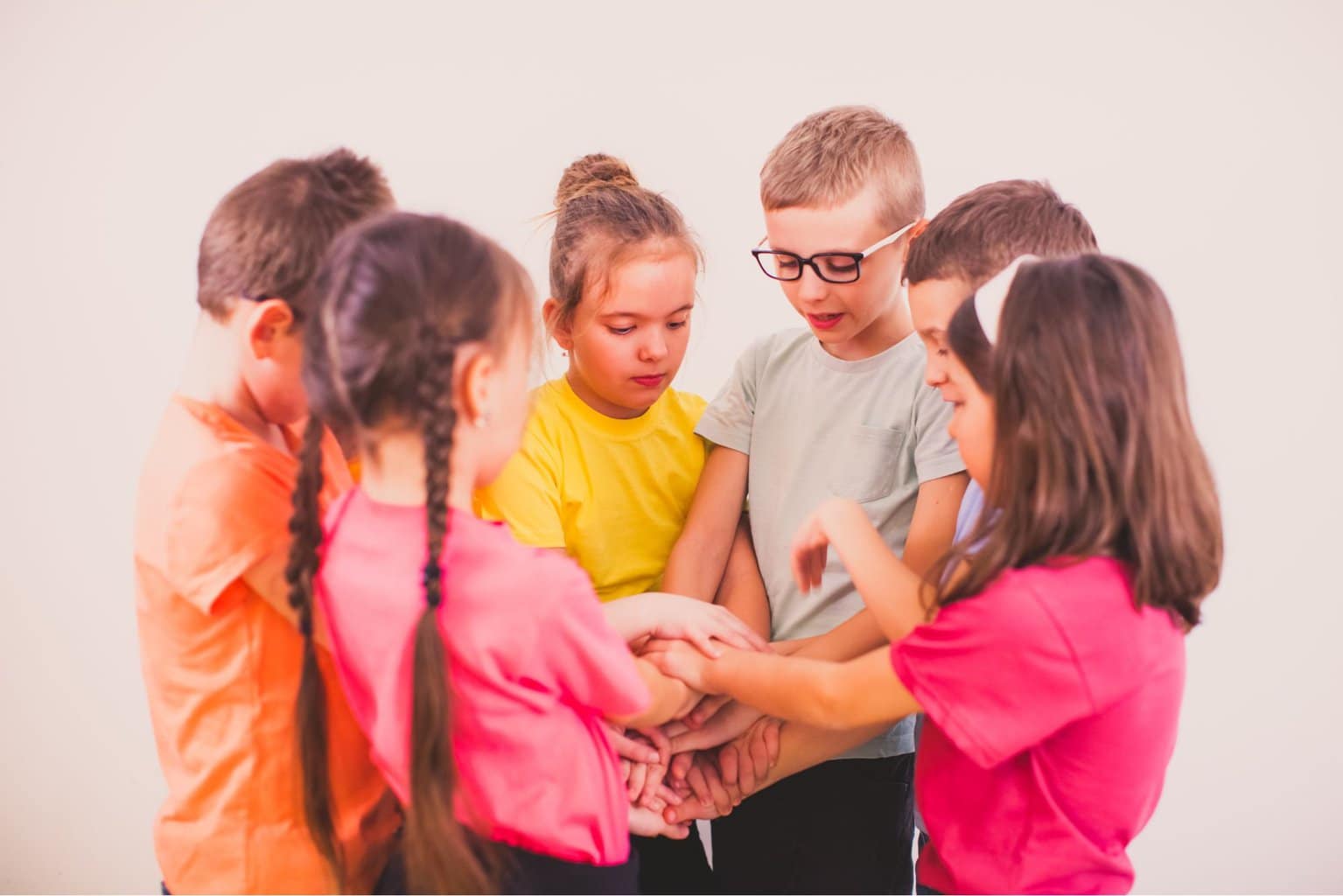 Kids with their hands together in a circle.