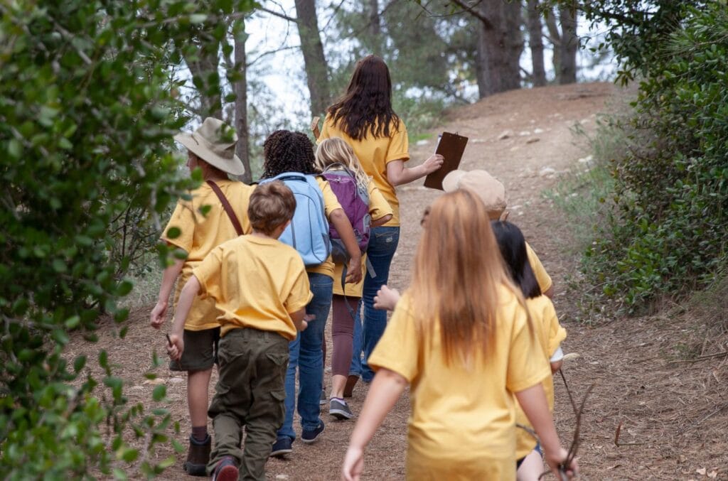 camp counselor with group of kids on a hike.